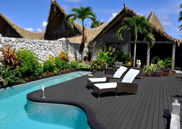 Poolside area with lounge chairs, pool, and thatched-roof buildings.