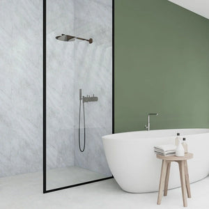 A modern bathroom scene featuring a walk-in shower enclosure with a black frame and matte black shower hardware, next to a white freestanding bathtub and a small wooden stool with bath accessories.
