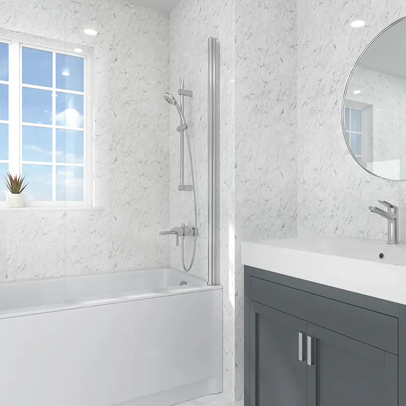 A modern bathroom scene featuring a white bathtub with a tall chrome shower screen, a white vanity with a dark gray cabinet, and a round mirror on a white marble-tiled wall.